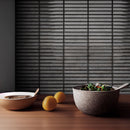 Bowl of salad on a wooden table with lemons and dark grey kit kat mosaic tiles on the wall.