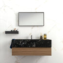 Bathroom vanity with black marble countertop and wooden base against a white marble effect tiled wall.
