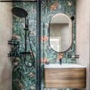 Bathroom with jungle pattern tiles, wooden vanity and oval mirror.