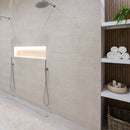 Shower with textured beige wall tiles, recess shelf and shelves with towels and candles.