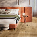 A bedroom interior featuring a bed with white bedding and a green throw, a terracotta headboard and light wooden flooring.