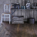 Rustic kitchen image with dark wooden flooring and walls and kitchen items on table.