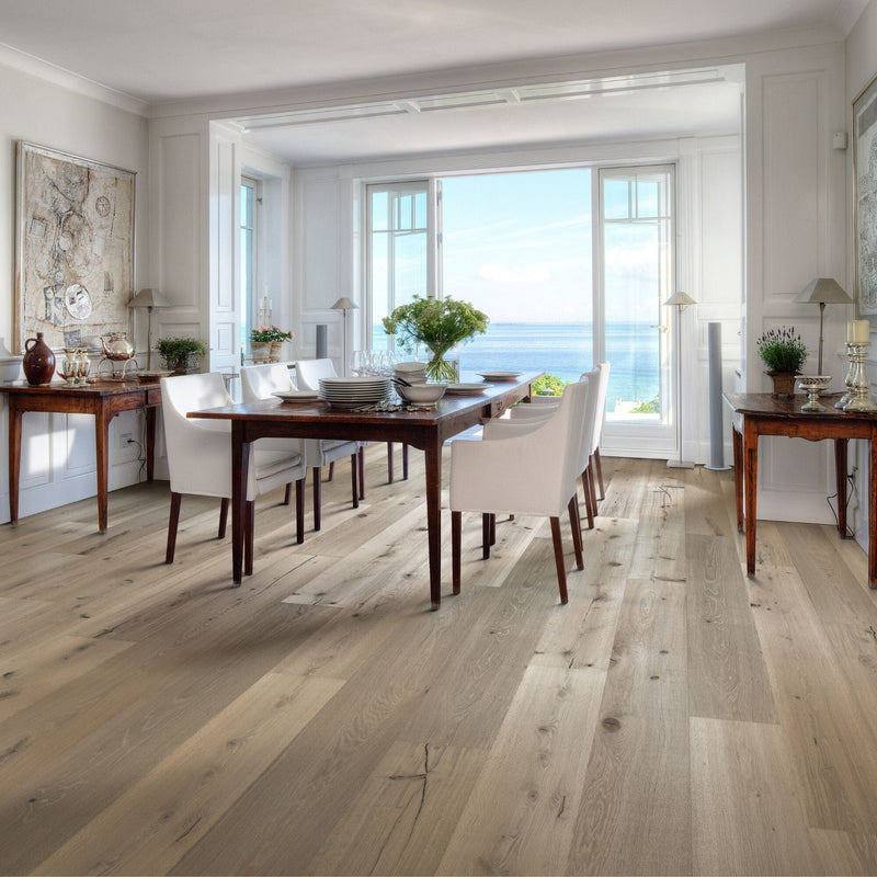 Thick pale wooden flooring in a dining room with a large window with a sea view.