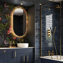 Modern bathroom with dark blue tiles, gold fixtures, and a decorative mirror.