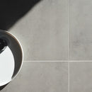 Close-up of gray tiles with a round object casting a shadow on the left side.