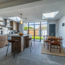 Kitchen with wooden cupboards, dining table and chairs and large grey floor tiles