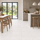 Bright green with taupe cupboards and pale stone effect floor tiles with a wooden table and wishbone style dining chairs.