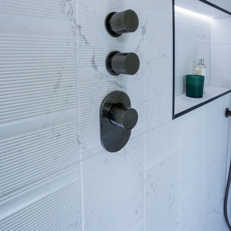 Black shower valve on marble effect wall tiles.