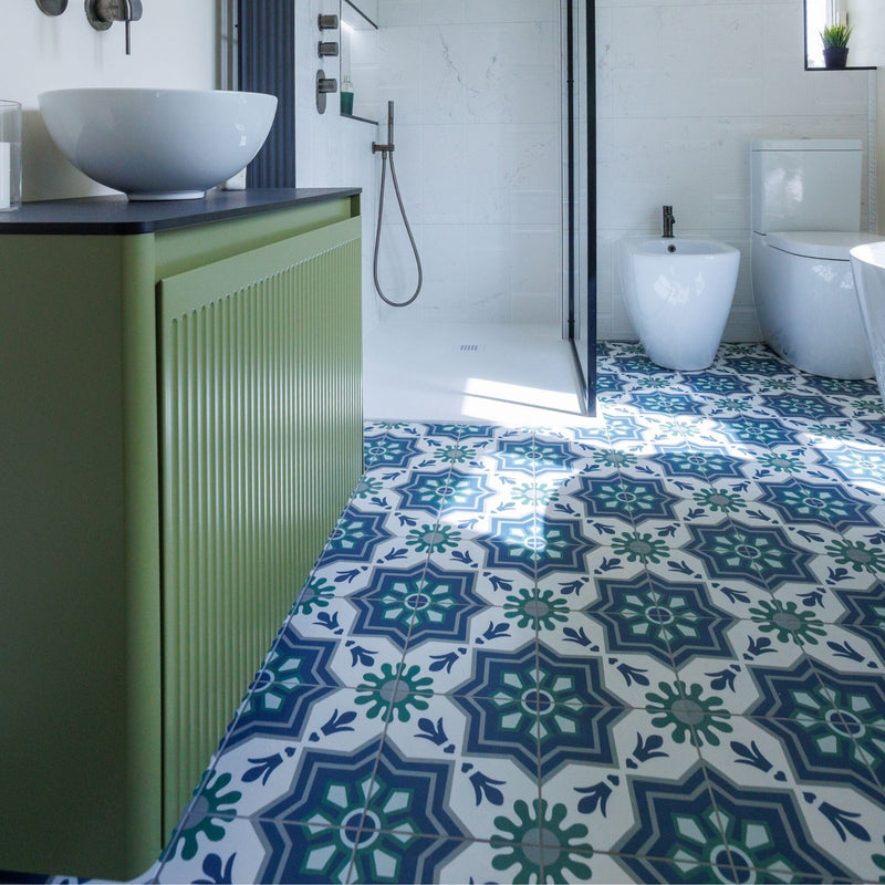 Bathroom with patterned tiles on the floor and a green vanity.