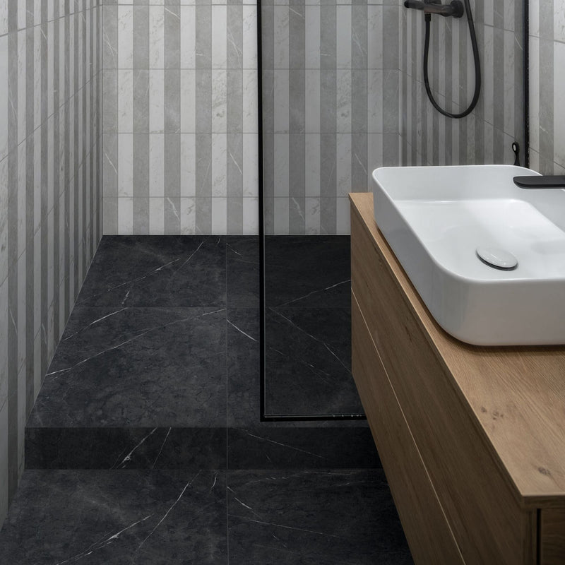 Bathroom with black marble effect floor tiles and grey and white metro tiles in striped wall design.