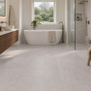 Light grey stone effect floor tiles in a modern, bright bathroom with a freestanding bathtub, glass shower enclosure, wooden vanity, and natural window view.