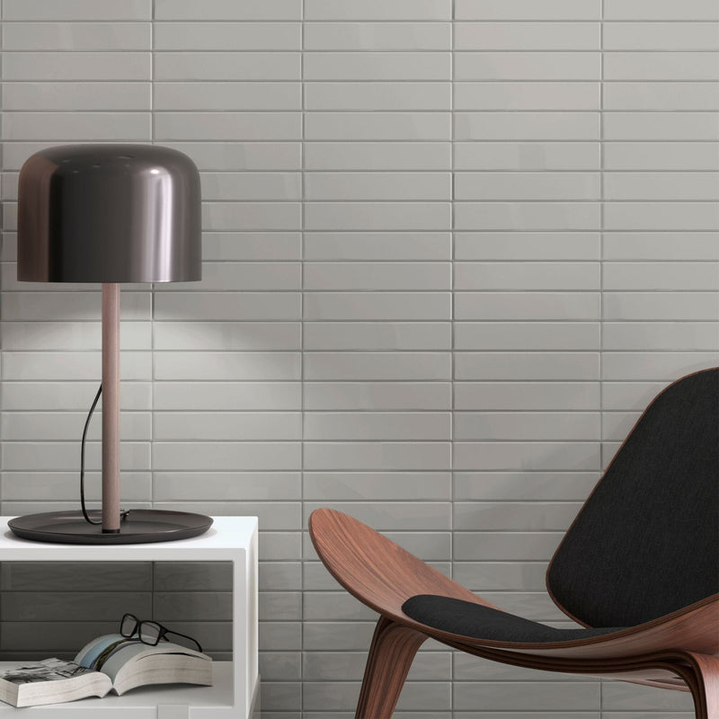 Modern interior with light grey wall tiles wooden chair and black table lamp.