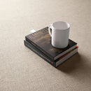 Beige fabric effect tile with a white cup and books.