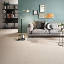 Living room featuring beige fabric effect floor tiles, a grey sofa, a black floor lamp and a teal wall with framed art.