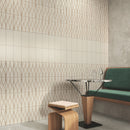 Tiled wall with a mixture of cream metro tiles stacked vertically, with a green bench, wooden stool and round table. 