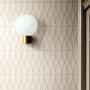 Wall with cream textured metro tiles stacked vertically and a round wall light with a brass fitting. 