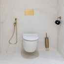 Modern bathroom with a wall-mounted toilet, brushed brass fixtures and a white marble effect tiled wall.