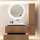 Bathroom vanity with wooden cabinets, round mirror, and lighting fixtures.