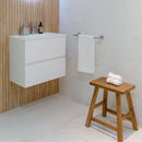 Bathroom with white vanity, wooden stool, ridged wood effect wall tiles and white floor and wall tiles.
