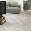 Gray sofa with a herringbone wood effect luxury vinyl floor and a black lamp.