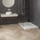 Modern bathroom with a shower area, dark grey walls and pale wood effect herringbone luxury vinyl flooring.