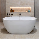 Modern white freestanding bathtub in a bathroom with beige tiled floor and walls and recess lighting.