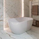 Modern bathroom with a freestanding white bathtub against a tiled wall.