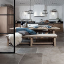 Modern kitchen with wooden dining table and bench and natural stone floor.