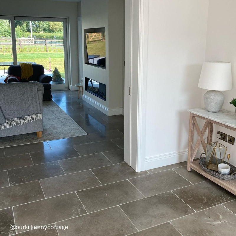 Living room with tiled floor, gray sofa, and television.