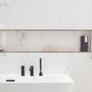 Bath with marble effect wall tiles and a black tap.