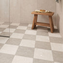 Bathroom with a checkerboard tiled floor in beige tones, beige wall tiles and a low wooden stool.