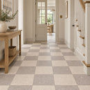 A hallway with a beige and grey checkerboard tiled floor with a light wood console table on the left and a staircase on the right.