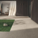 Outdoor patio area with large square taupe outdoor paving and a grass area.