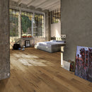 Modern bedroom with large windows, wooden floor and artwork against the wall.