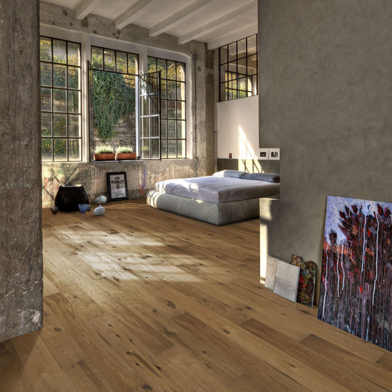 Modern bedroom with large windows, wooden floor and artwork against the wall.