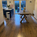 Kitchen with wooden table and oak wood floor, showing a view of the garden through a sliding glass door.
