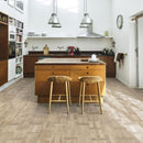 Kitchen with an island and wood bar stools and pale engineered wood flooring laid in a Dutch pattern.