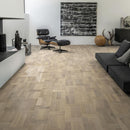 Living area with a dark dark grey and leather armchair and pale engineered wood flooring laid in a Dutch pattern.