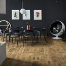 Dining area with a dark table and chairs and honey coloured engineered wood flooring laid in a Dutch pattern.