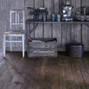 Rustic kitchen image with dark wooden flooring and walls and kitchen items on table.