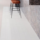 Stools with white natural stone herringbone mosaic tiles on floor.