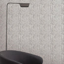 Gray herringbone wall mosaic tiles with a black floor lamp and chair.
