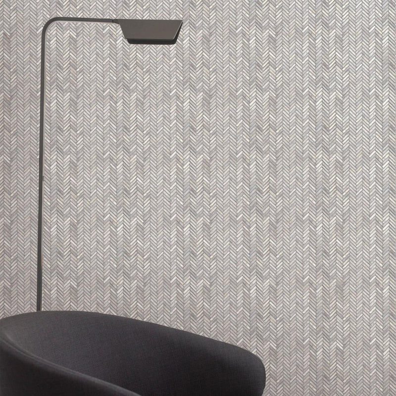 Gray herringbone wall mosaic tiles with a black floor lamp and chair.