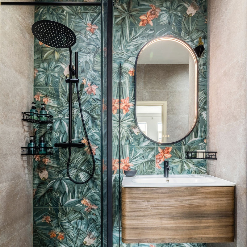 Bathroom with jungle pattern tiles, wooden vanity and oval mirror.