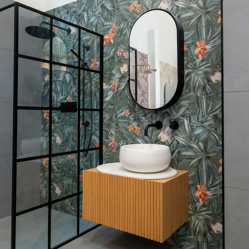 Bathroom with tropical print wall tiles, wooden vanity and black bathroom fittings