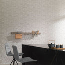 Modern kitchen with stone-textured wall tiles, black island and grey chairs.
