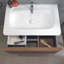 Chrome tap and matt white basin and open vanity unit drawer.