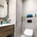 Modern bathroom with toilet, sink, and shelves with towels and toiletries.