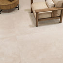 Large-format light beige stone-look floor tiles shown in a modern interior setting with a wooden armchair.