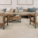 A styled living room scene featuring large, light beige floor tiles that match the neutral beige sofa, wooden armchairs, and round rustic coffee table.